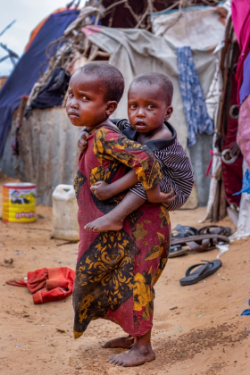 Two young Somali children standing outside a refugee camp.